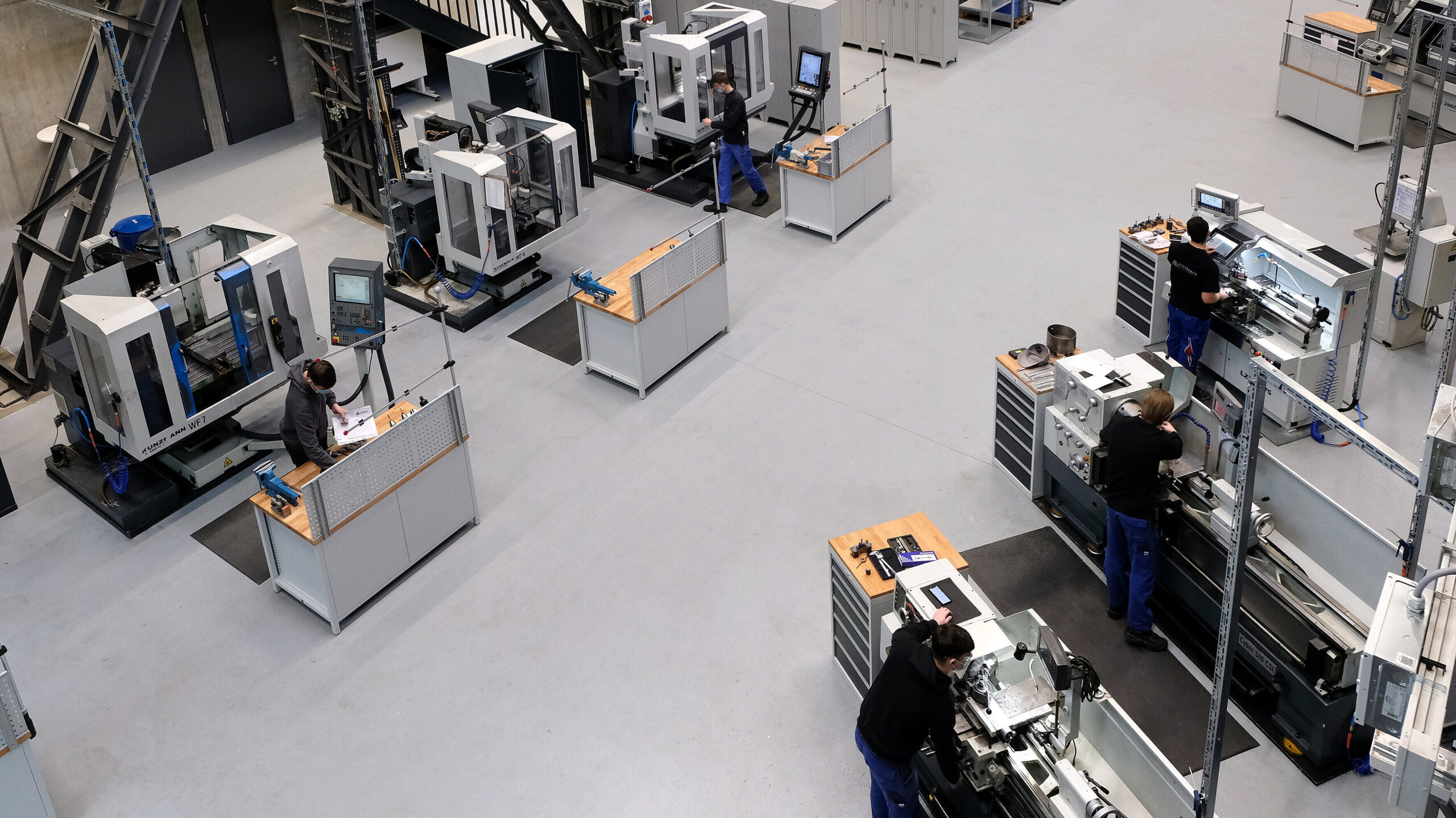 Smarte Lernfabrik Buschhütten von innen. Personen, die an CNC-Fräs- und Drehmaschinen arbeiten.